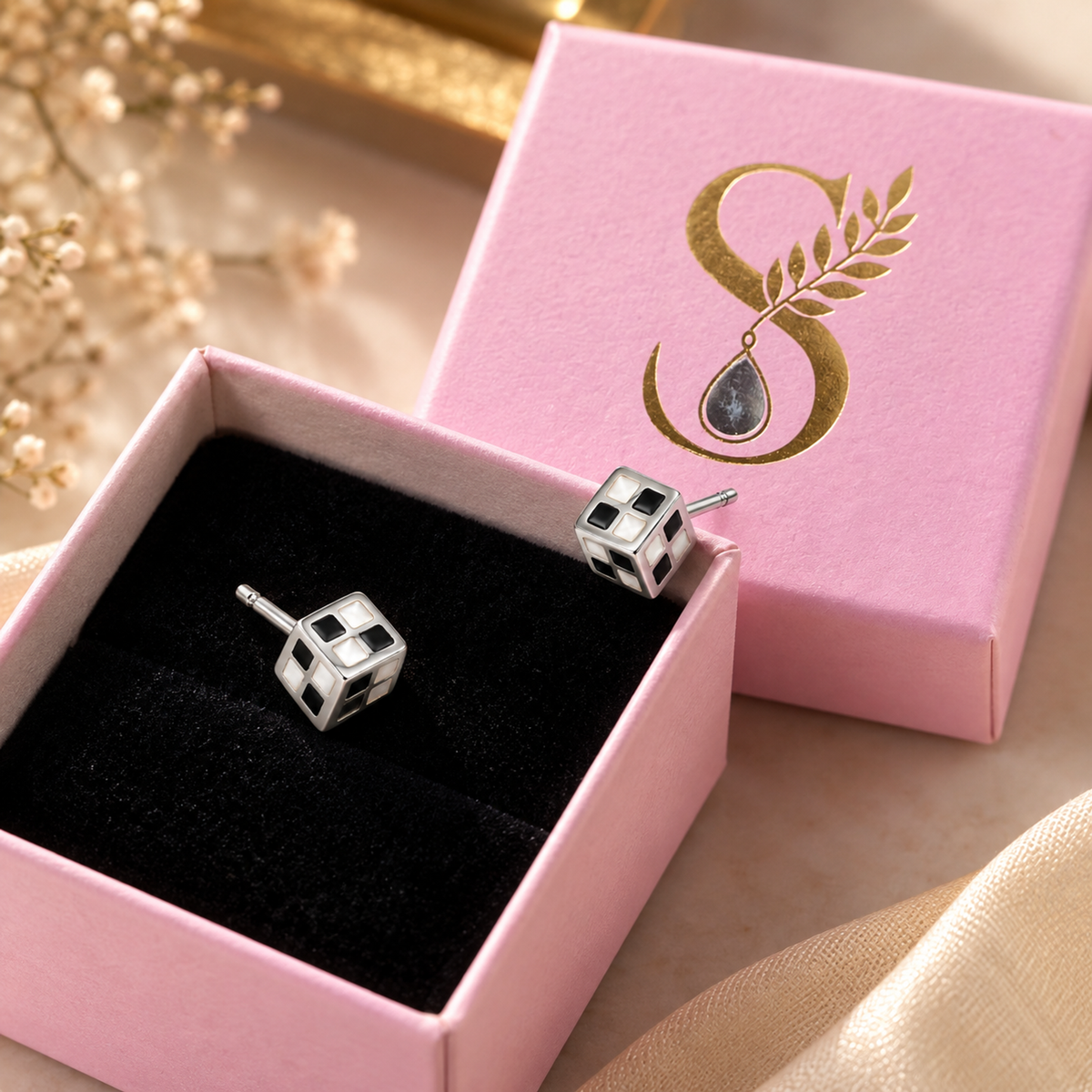 Cube stud earring inside a pale pink Silvanya jewellery box with black velvet interior.
