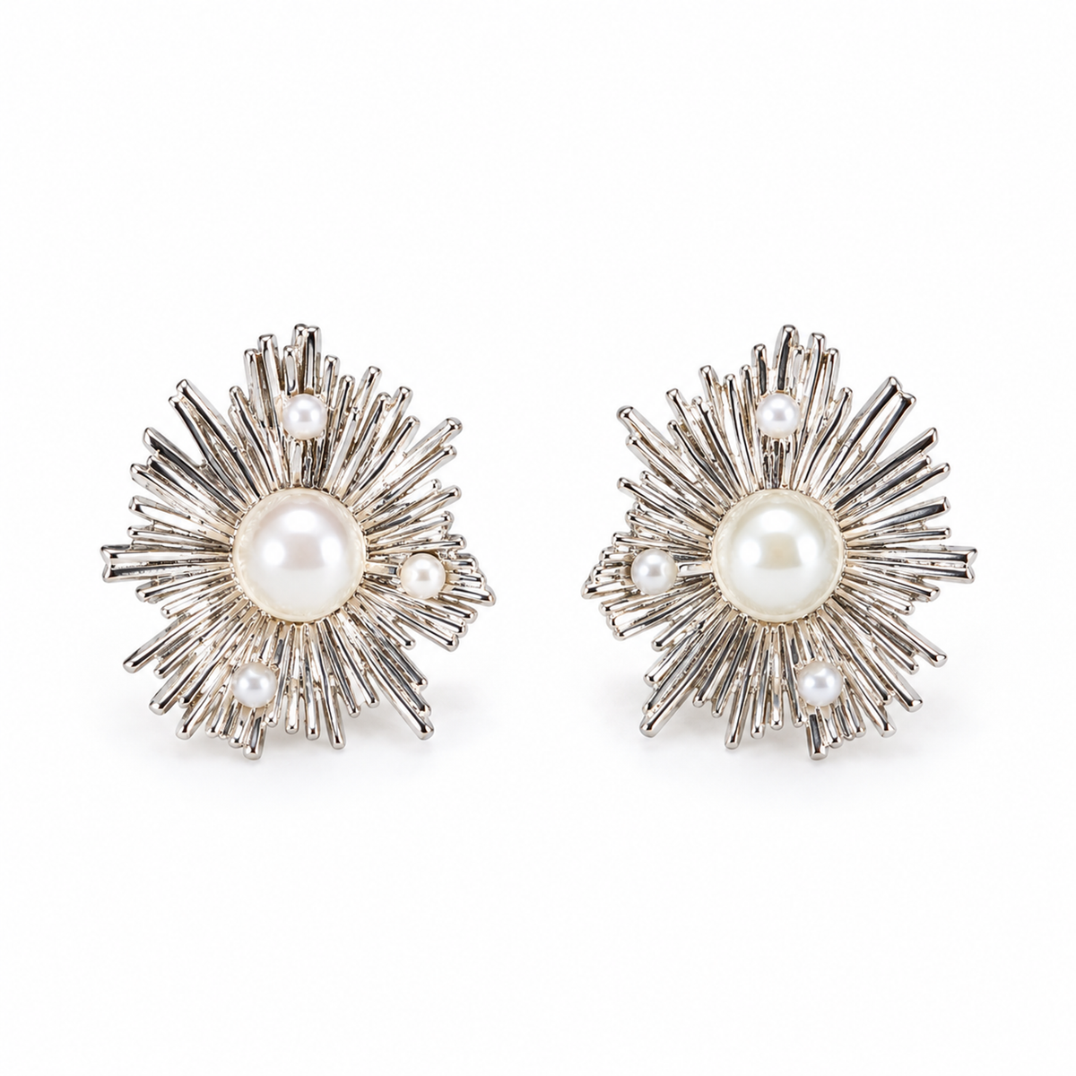 A pair of silver sunburst stud earrings with central pearls on a plain white background.