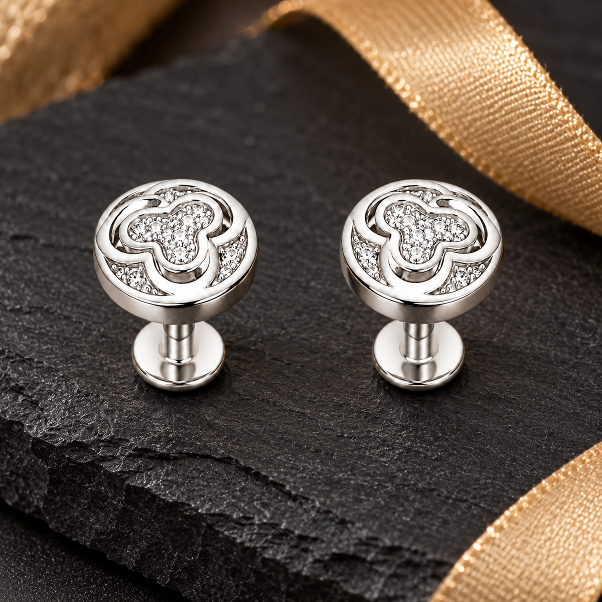 Silver swirl studs styled on dark slate with warm gold accents