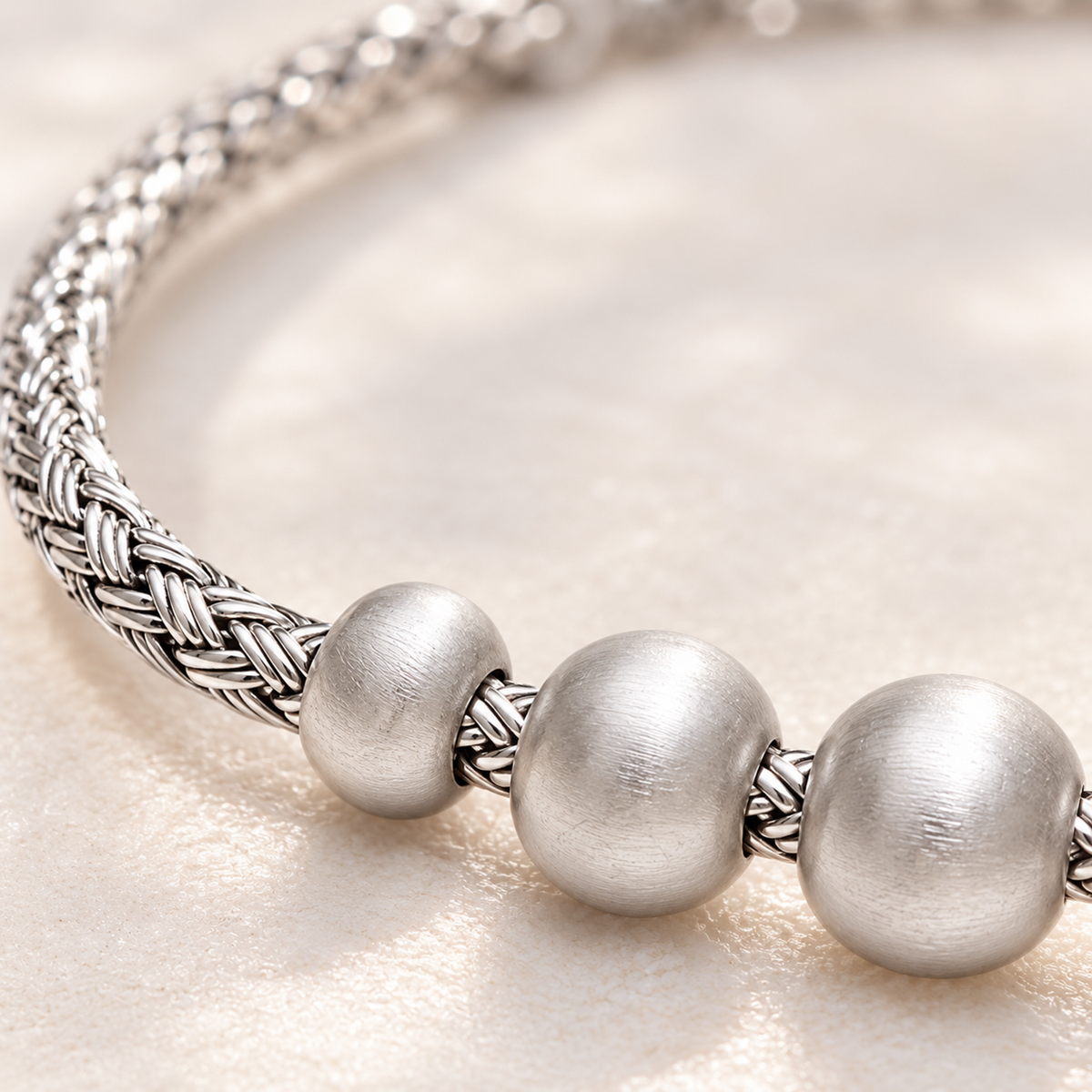 Detailed macro close-up showing intricate woven silver strands meeting satin-finish round silver beads.