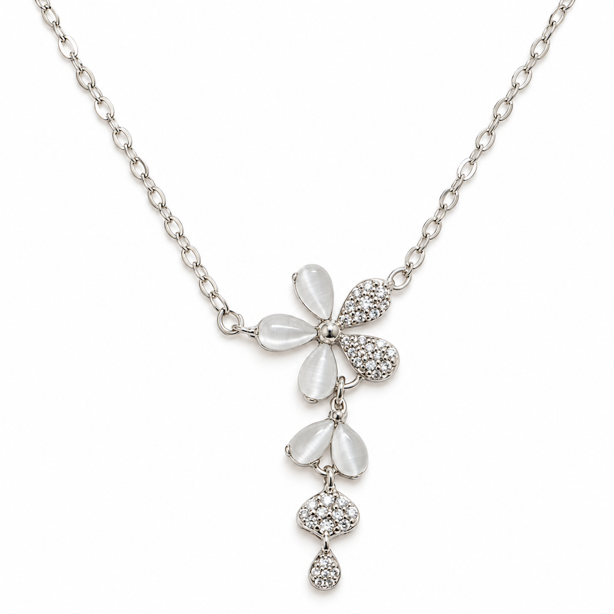 A silver floral pendant necklace with white cat's eye and cubic zirconia petals, laid flat on a white background.