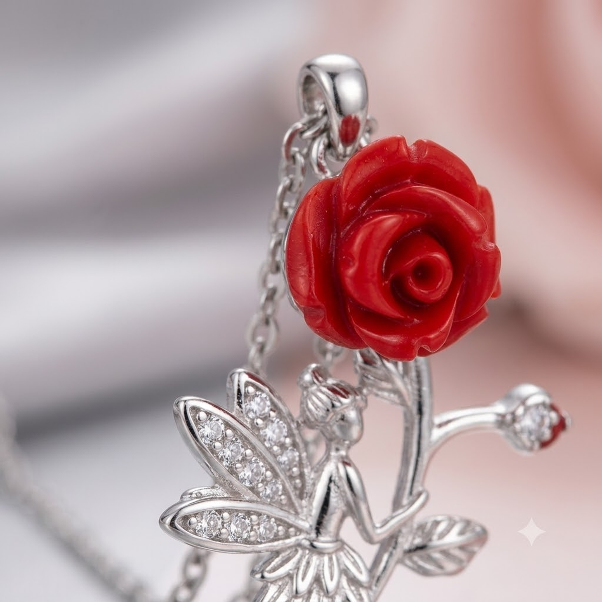 Extreme close-up of the carved red rose and cubic zirconia wings of the silver fairy pendant.