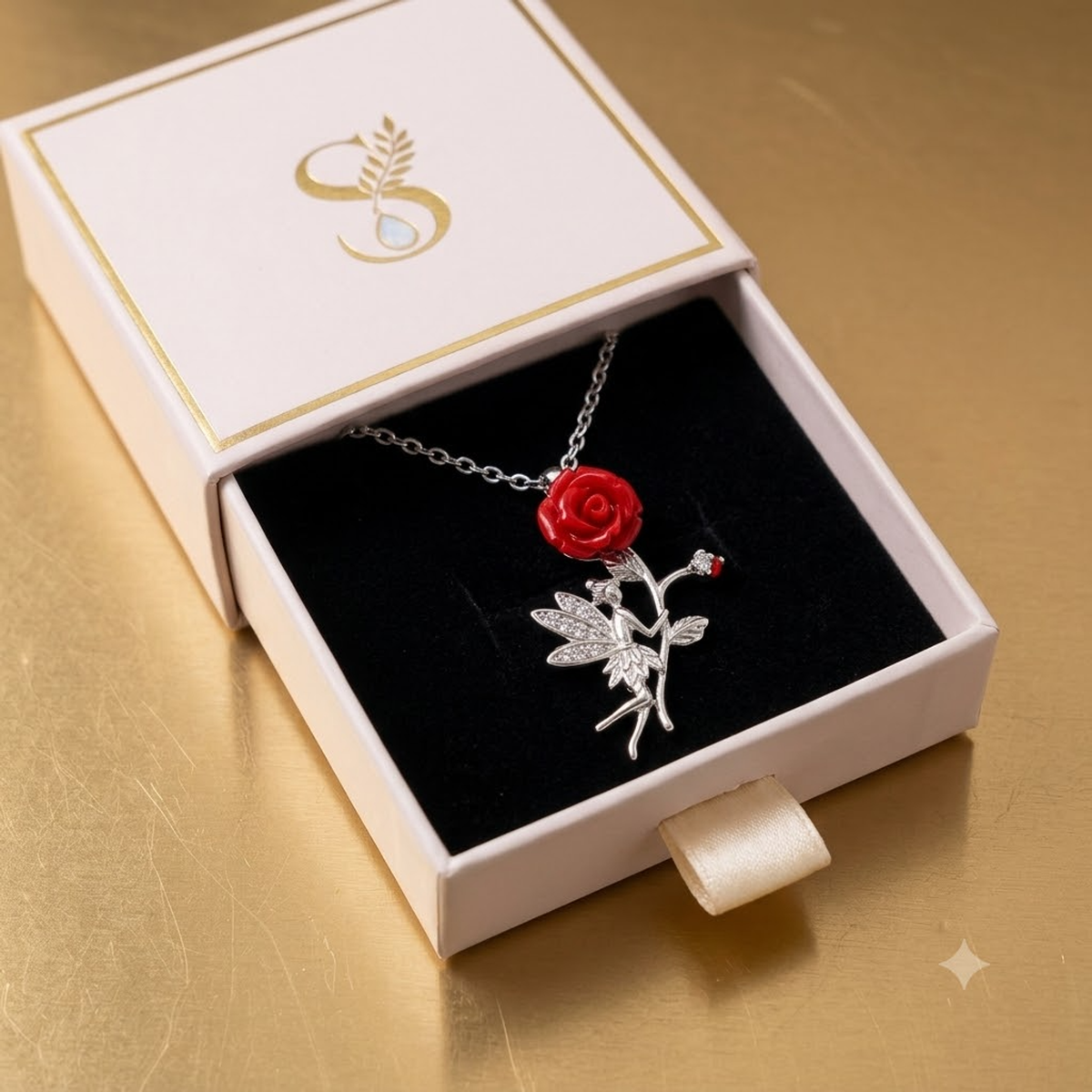 Silver fairy necklace nestled on the black velvet interior of a small pale pink Silvanya box with a gold monogram.