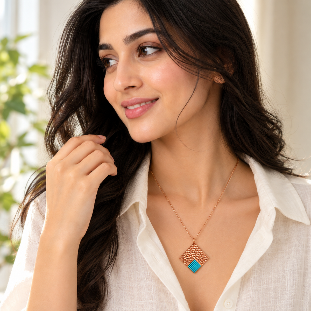 Model wearing a diamond-shaped rose gold necklace with turquoise detailing.