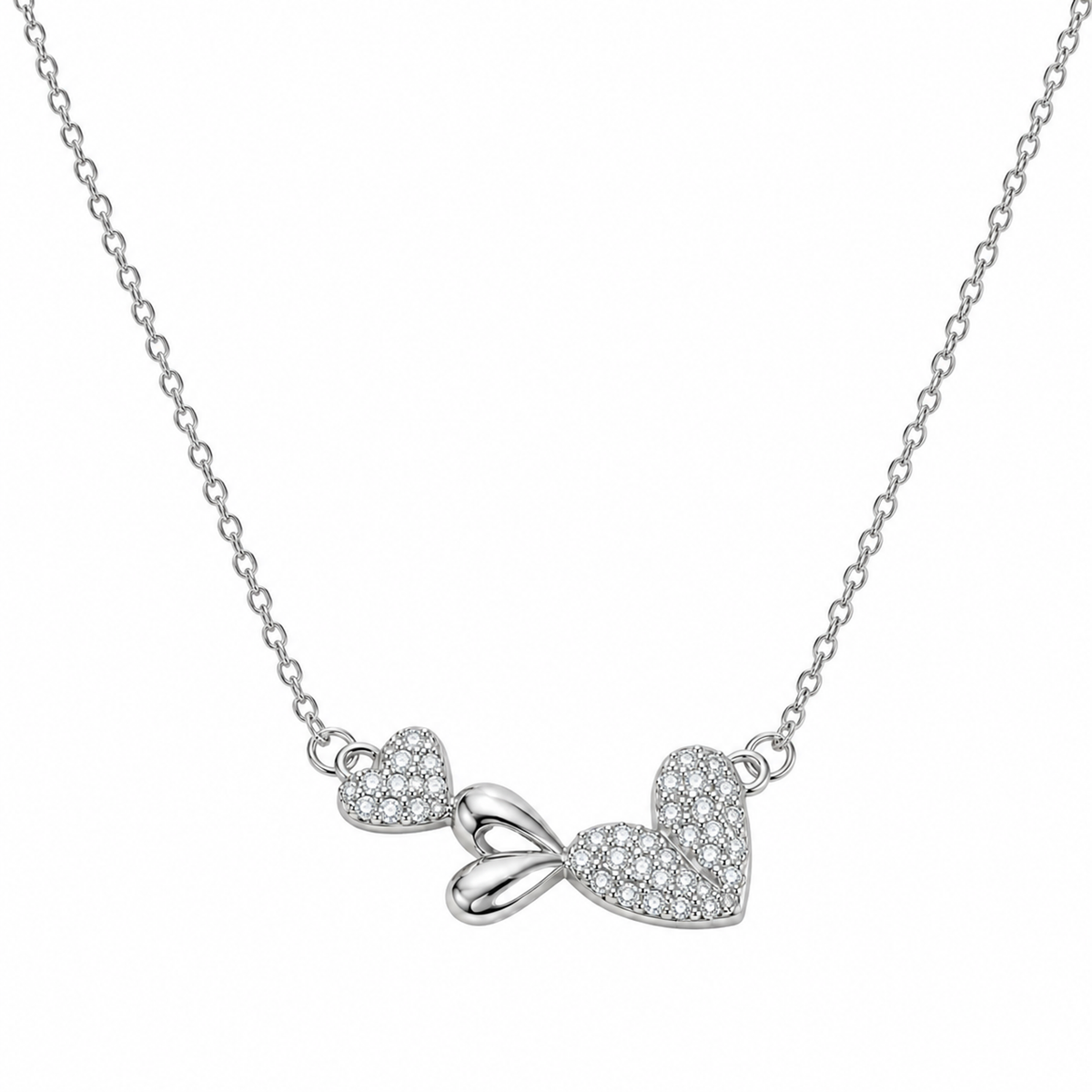 Silver necklace with dual heart and bow pendant centered on a clean white background.