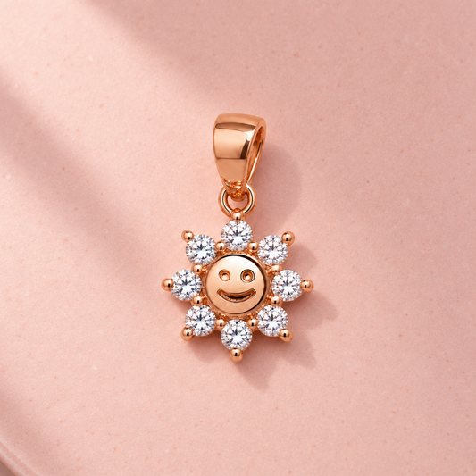 Rose gold smiling sun pendant resting on a matte blush pink ceramic tile.