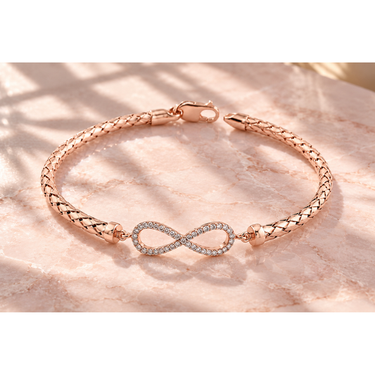 Rose gold mesh infinity bracelet resting on smooth blush pink marble in natural morning sunlight.
