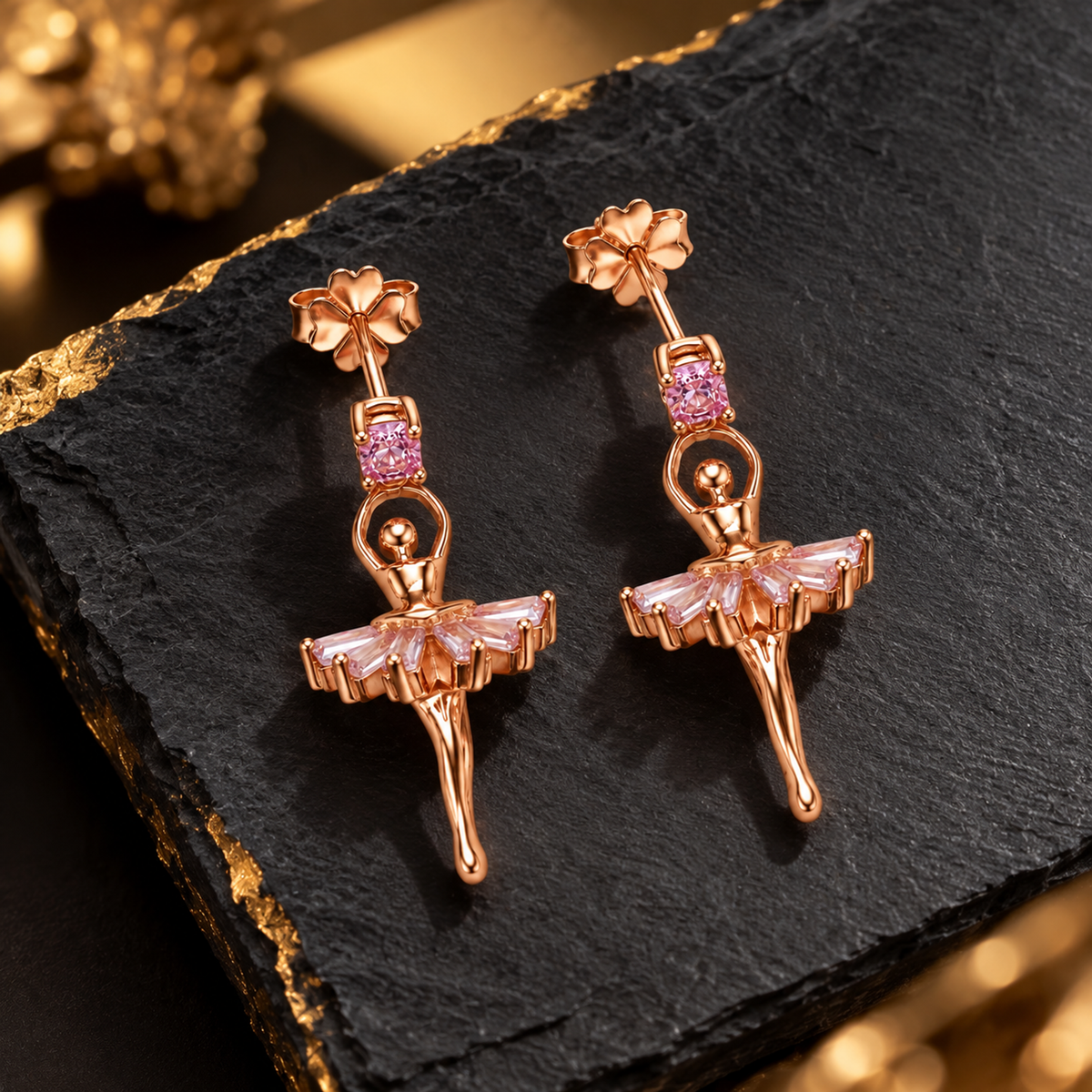 Ballerina drop earrings displayed on a matte black slate surface with warm lighting.