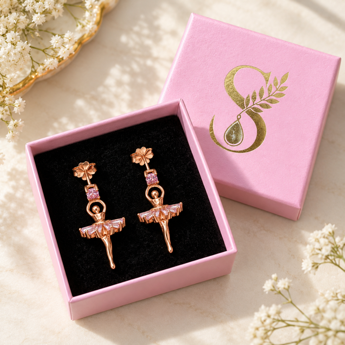 Rose gold ballerina earrings displayed inside a pale pink Silvanya gift box on black velvet.