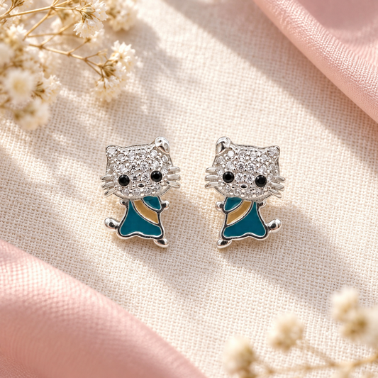 Feline silver stud earrings positioned on soft ivory textured linen background.