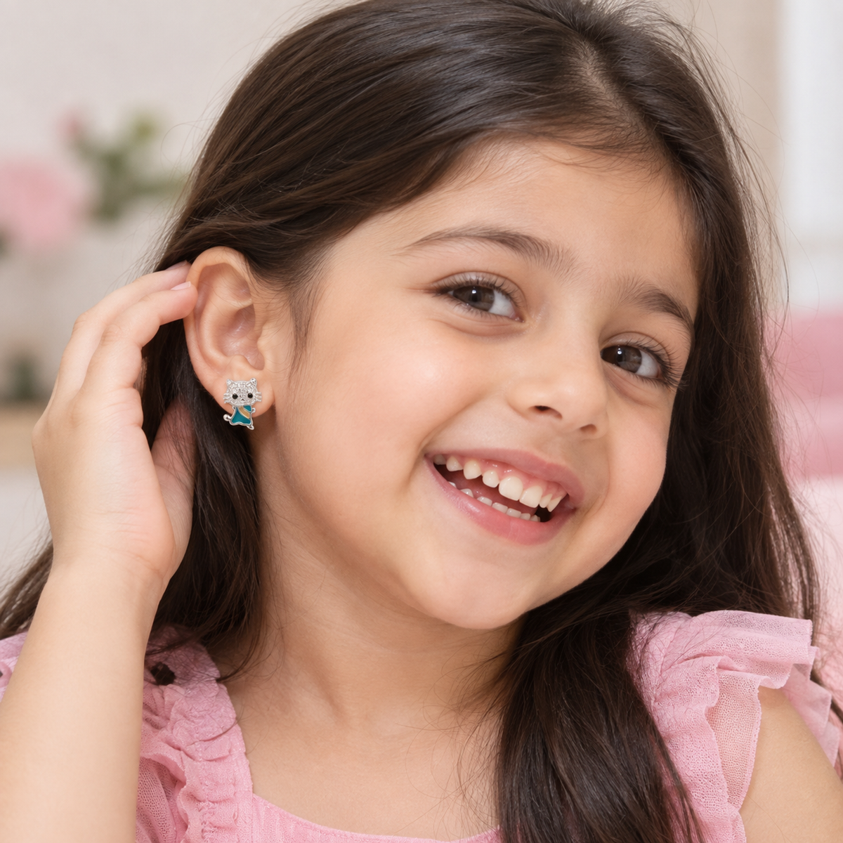 Close-up of a child wearing a silver feline stud earring while smiling delightfully.