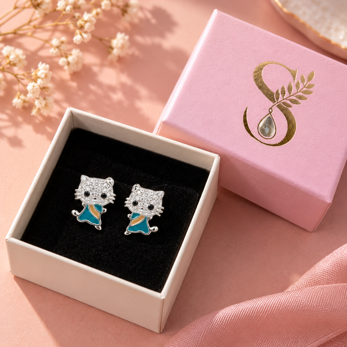 Silver feline stud earrings presented inside a pale pink Silvanya gift box with black velvet lining.