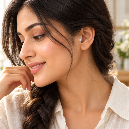 A close-up of a woman wearing a tiny silver clover stud in her ear piercing.