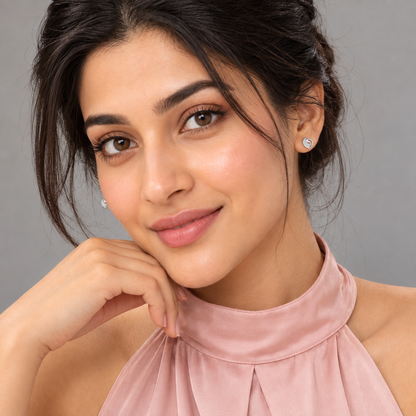 A woman with her hair in a bun wearing silver clover-shaped studs in her ear lobes.