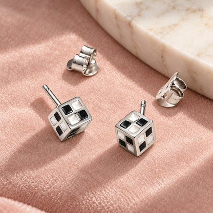 Monochrome cube stud earrings on blush pink velvet near an ivory marble tray.