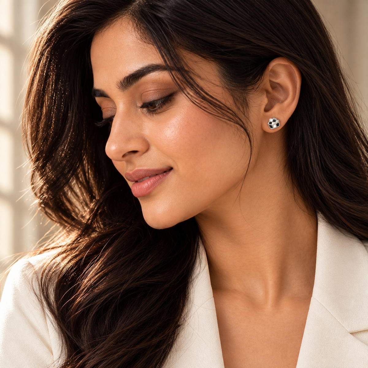 Woman wearing a monochrome checkerboard cube stud earring with an ivory blazer.