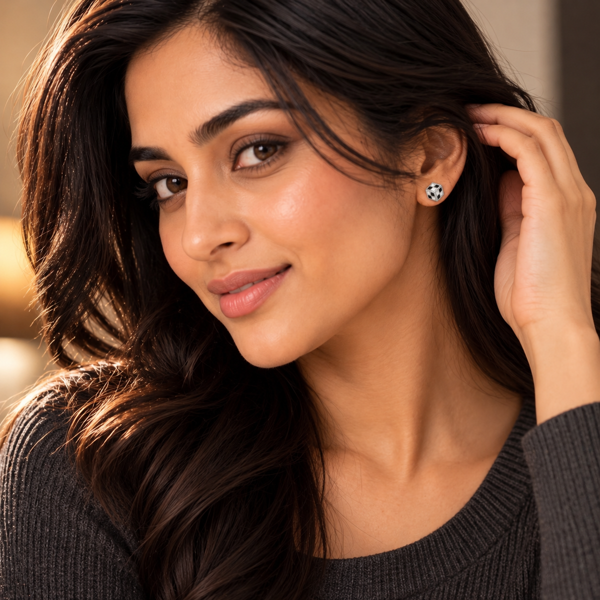 Woman smiling while wearing a cube stud earring with black and white checkerboard detailing.