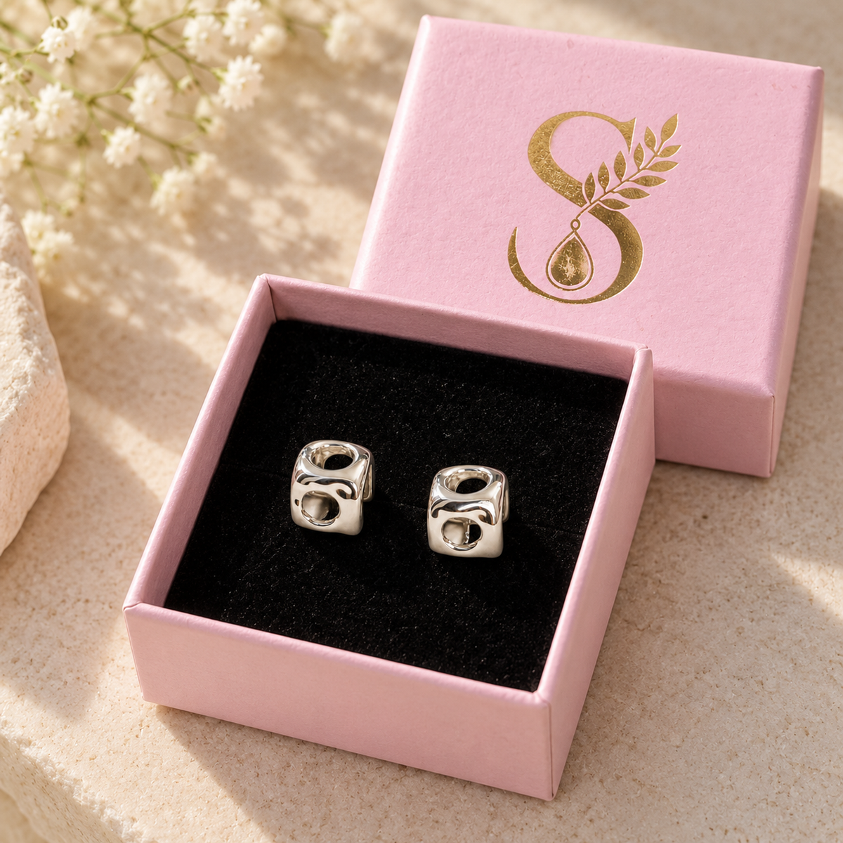 Silvanya blush pink gift box open with black velvet interior displaying silver cube stud earrings.