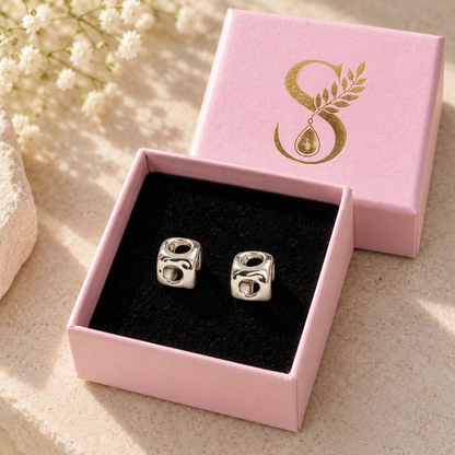 Silvanya blush pink gift box open with black velvet interior displaying silver cube stud earrings.