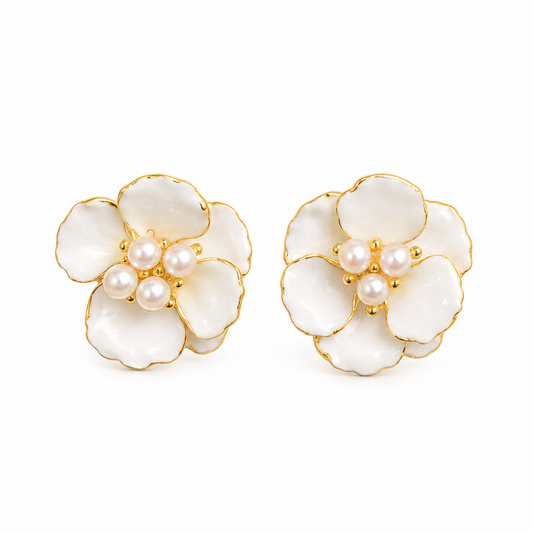 Pair of flower-shaped stud earrings with white enamel petals and central pearls on a seamless white background.