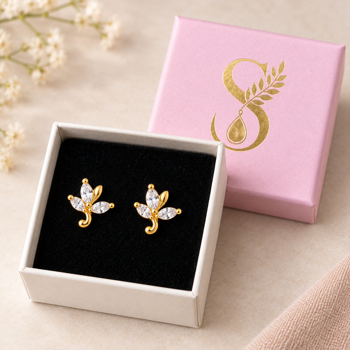 Gold leaf stud earrings presented inside the signature Silvanya pale pink box on black velvet.