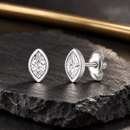 Silver stud earrings on a dark textured slate background with subtle gold accents.