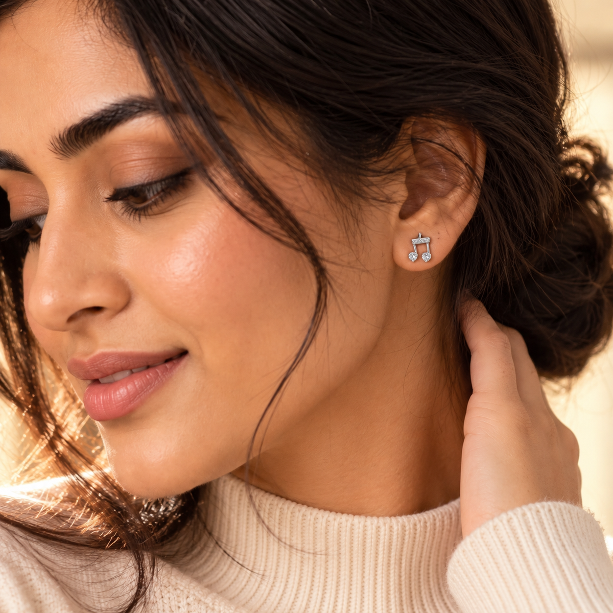 Close-up of a woman wearing the silver musical note stud earring on her lobe.
