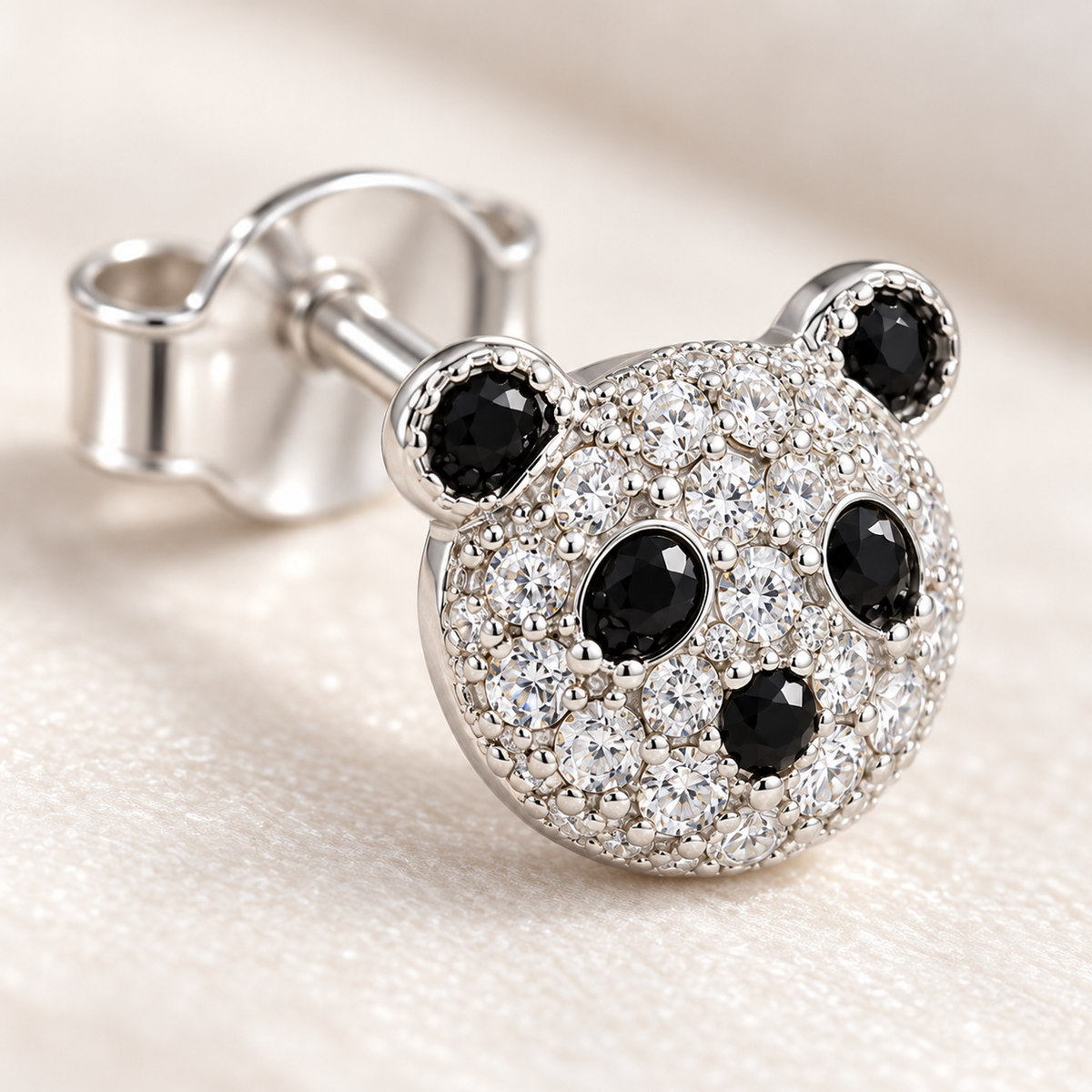 Macro detail of the micro-pavé clear and black stones on a silver panda stud earring.