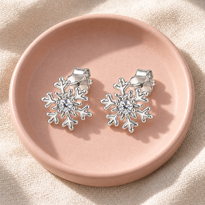 Silver snowflake studs on a dark slate surface with subtle gold accents.