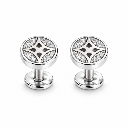 Silver star pave stud earrings resting on an ivory stone tile next to blush pink linen fabric.