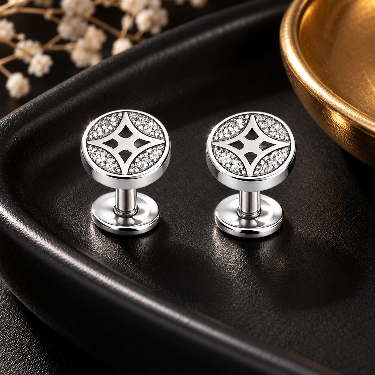 Round star silver studs placed on a dark matte black dish next to a warm gold accent dish.