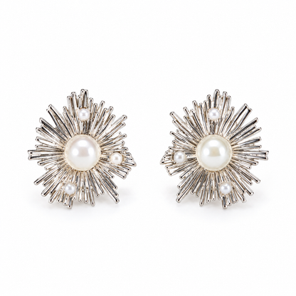A pair of silver sunburst stud earrings with central pearls on a plain white background.