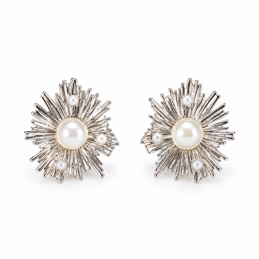 A pair of silver sunburst stud earrings with central pearls on a plain white background.