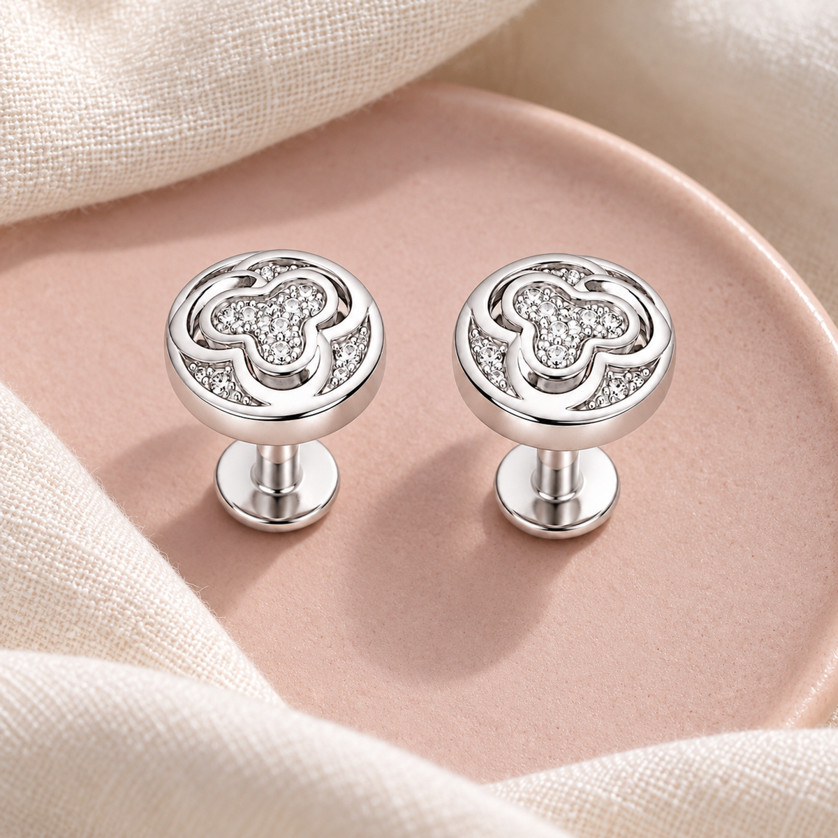 Silver stud earrings displayed on blush pink ceramic and ivory linen