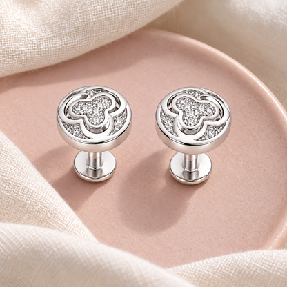 Silver stud earrings displayed on blush pink ceramic and ivory linen