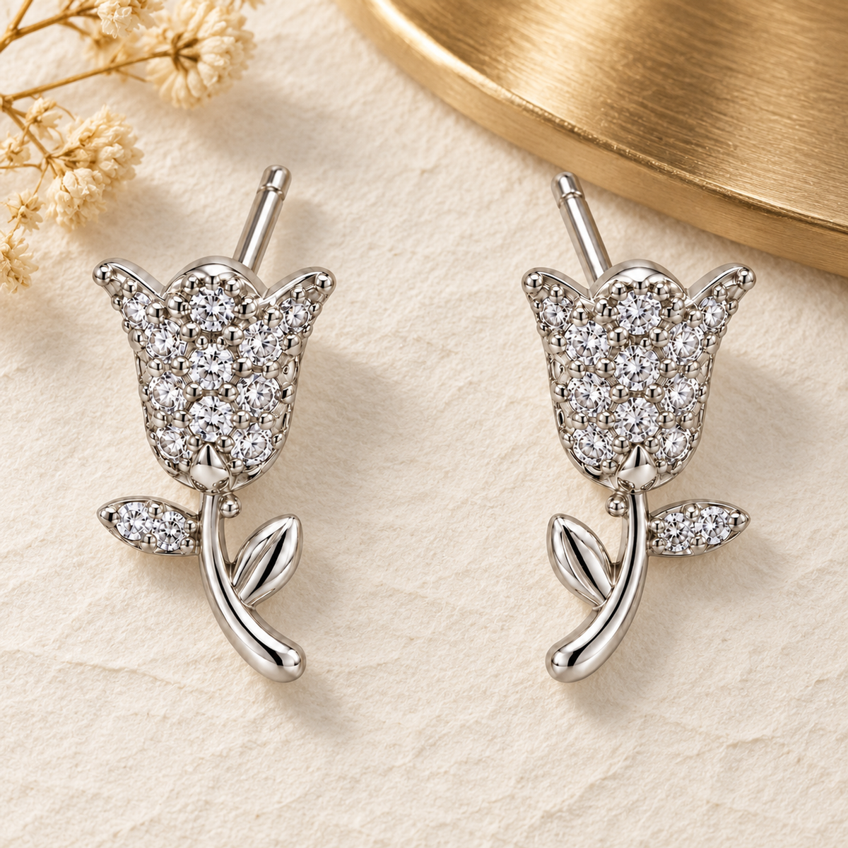 Silver tulip earrings resting on textured ivory paper with soft gold accents.