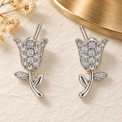 Silver tulip earrings resting on textured ivory paper with soft gold accents.