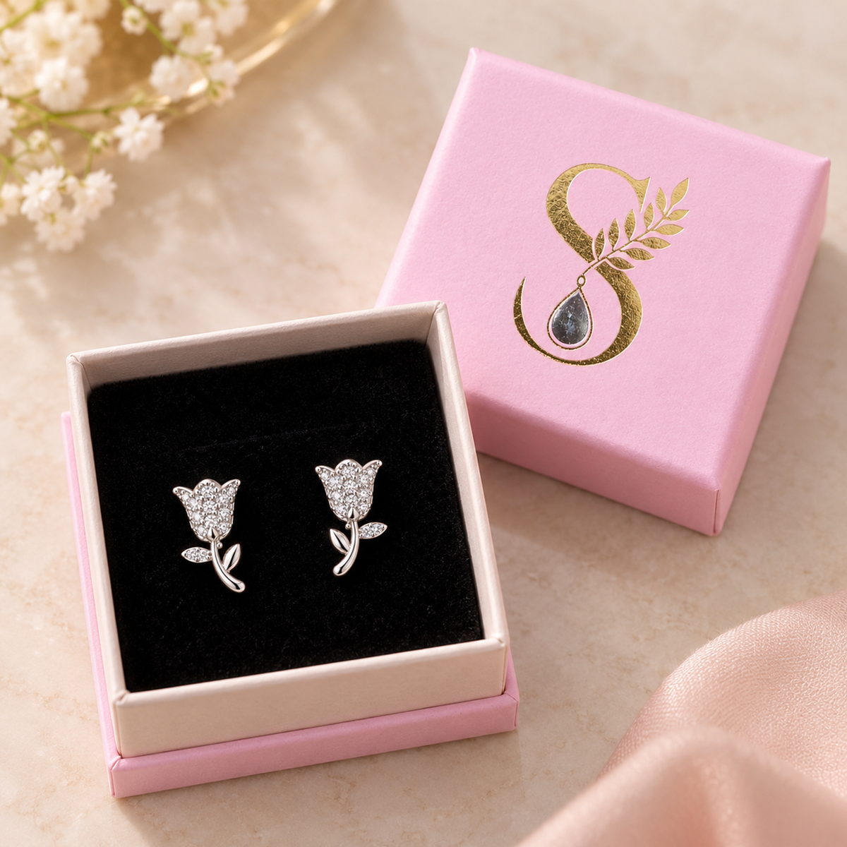 Silver tulip stud earrings inside a pink Silvanya gift box on black velvet.