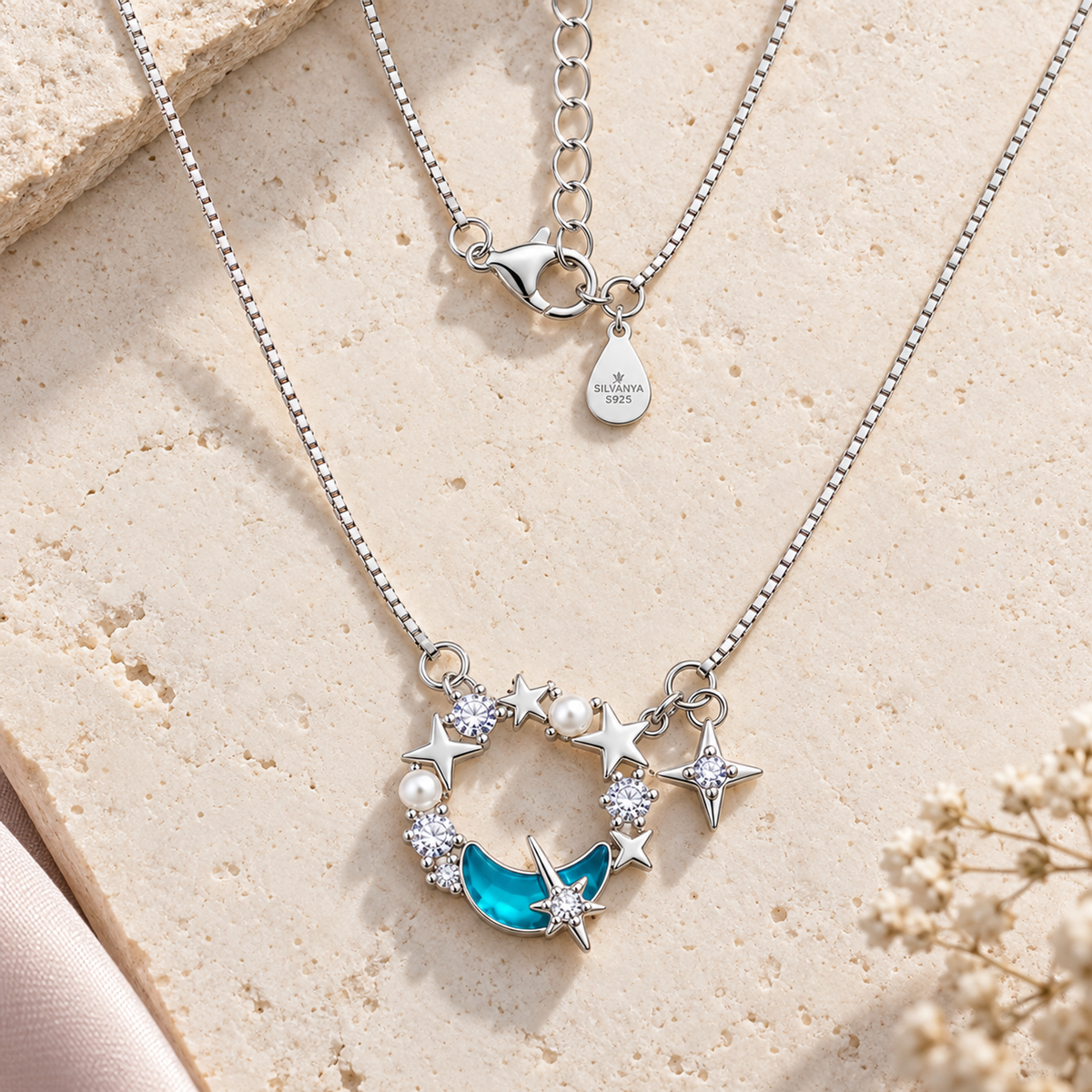 Flat lay of silver celestial wreath necklace on white ivory limestone surface.