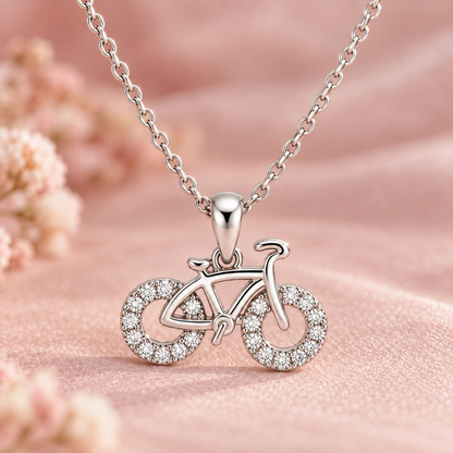 Macro view showing the stone-set wheels and polished silver frame of the bicycle pendant.