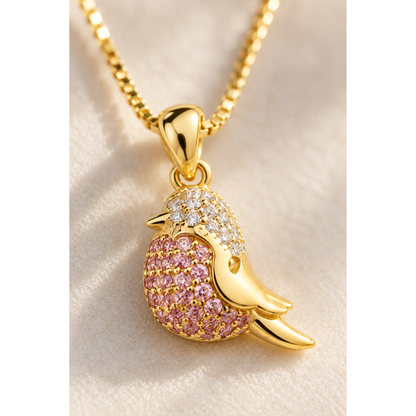Extreme close-up of the delicate pavé set pink and clear stones on the gold bird pendant.