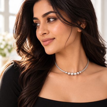 Model Noya wearing a braided silver neckband choker, turned profile in a black top.