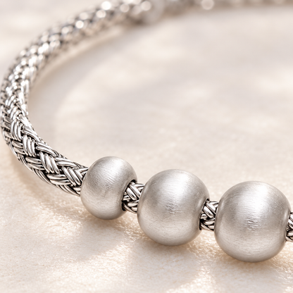 Detailed macro close-up showing intricate woven silver strands meeting satin-finish round silver beads.