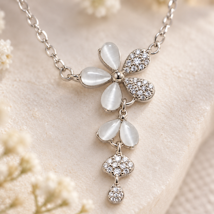 An extreme close-up of a silver flower pendant showing detailed cubic zirconia settings and cat's eye stones.