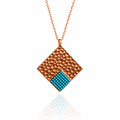 Diamond-shaped rose gold pendant with blue turquoise accent on white background.