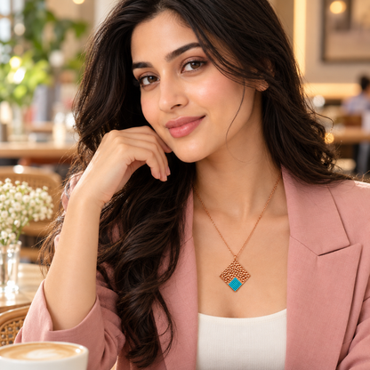 Woman in blush blazer wearing delicate turquoise rose gold pendant.