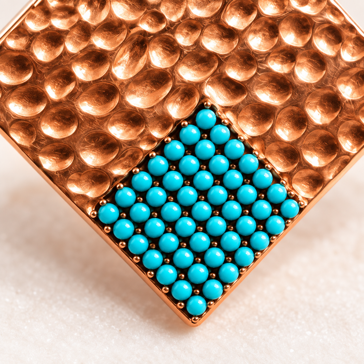 Macro shot of turquoise pave beads set into hammered rose gold metal.