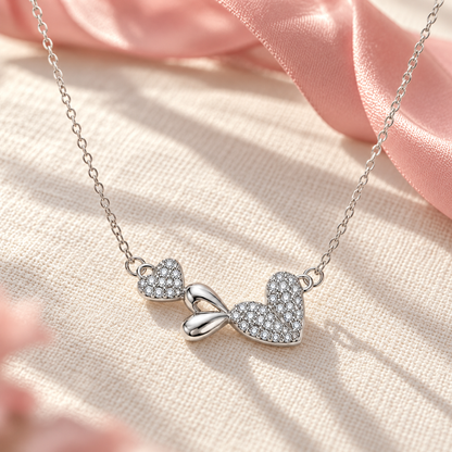 Silver heart necklace resting on ivory linen with soft ribbon accents.