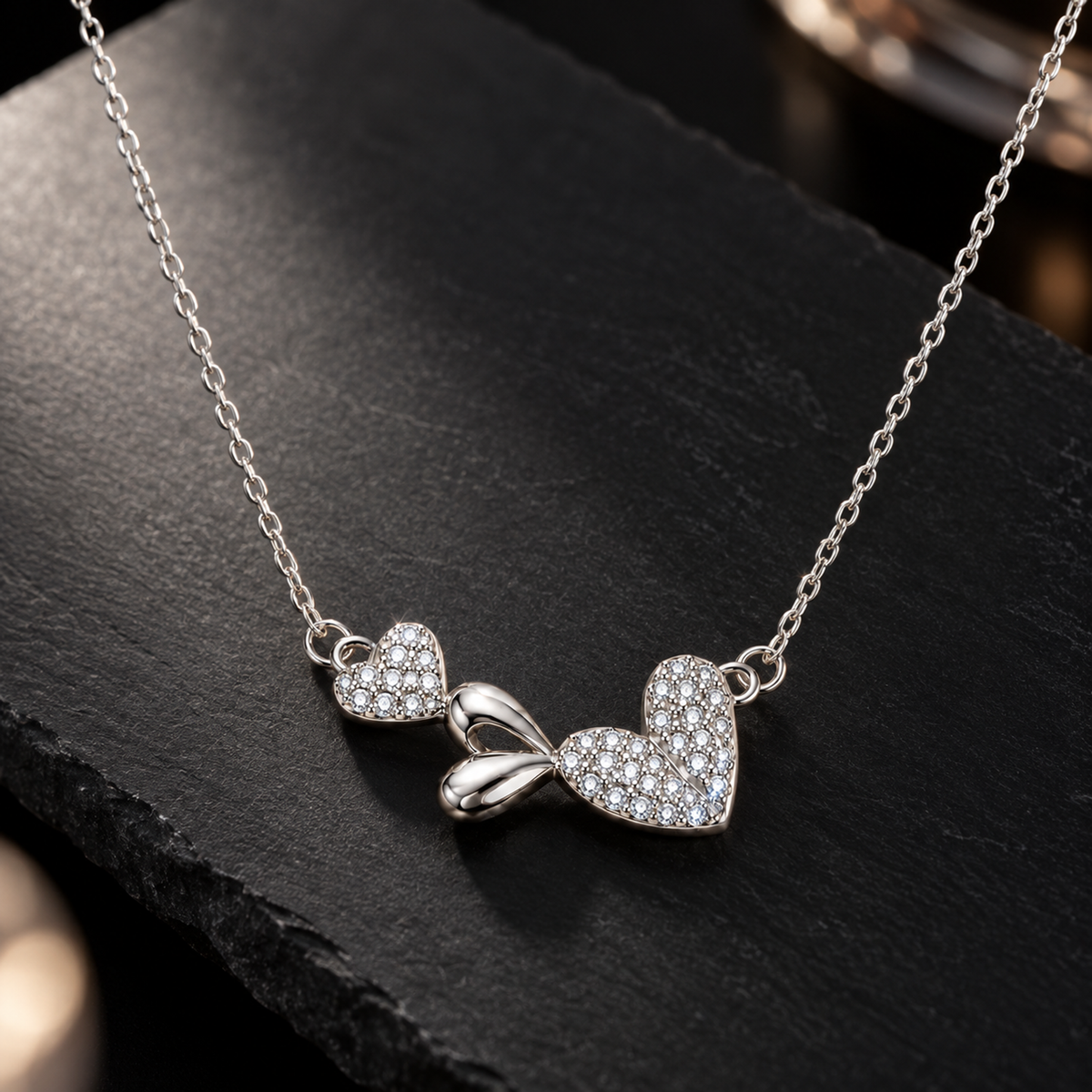 Silver heart pendant necklace resting on a sleek matte black slate surface.