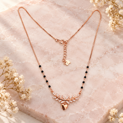 Rose gold infinity mangalsutra styled on blush pink marble with cream dried botanicals.